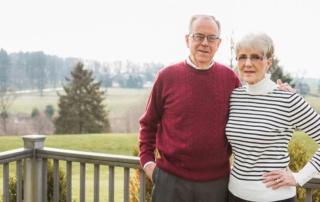 Smiling couple standing on their porch.