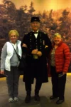 Senior women standing with man dressed in Civil War uniform.