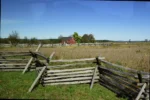 Wooden fence surrounding a large, open field.