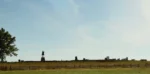 An open field in Gettysburg with statues in the distance.