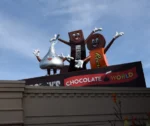 Hershey's billboard featuring a hershey kiss, chocolate bar, and Reeses cup with faces, arms and legs.