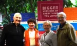 Two smiling couples standing outdoors together.