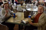 Smiling senior women eating milkshakes at a table.