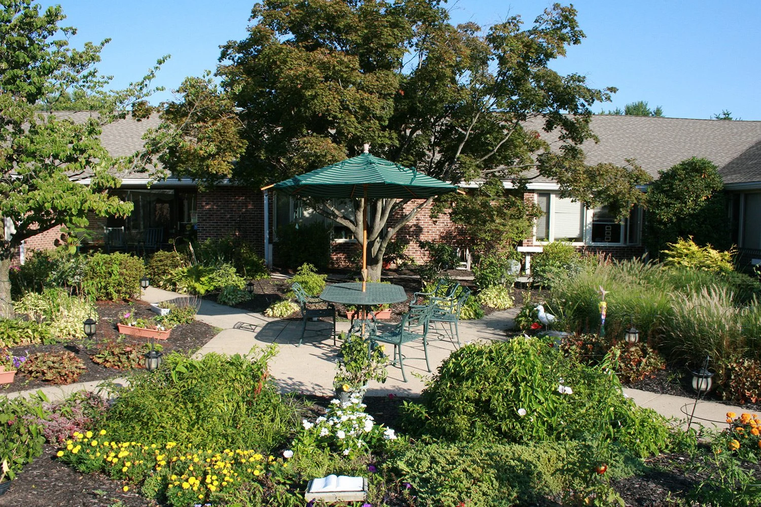 Masonic Village at Warminster courtyard with picnic table in the center, surrounded by flowers and plants.