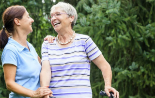 Two women stand laughing together outdoors.