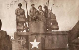 Faded photo of a group of five soldiers standing on tank during World War II