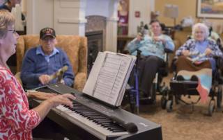 Residents and staff smile and laugh during a music therapy session at the Masonic Village at Elizabethtown.