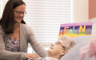 Smiling woman performing healing touch for senior woman.