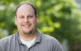 John Lebzelter, a smiling man with short brown hair standing outdoors.