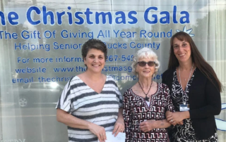 Three women present check to the Christmas Gala