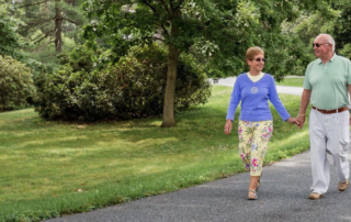 Senior couple holding hands while walking on path together.