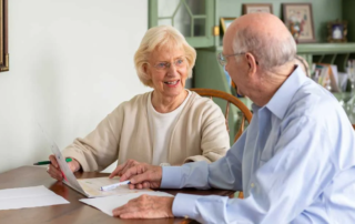 John & Louise Meister, a senior couple working on paperwork together at a table.