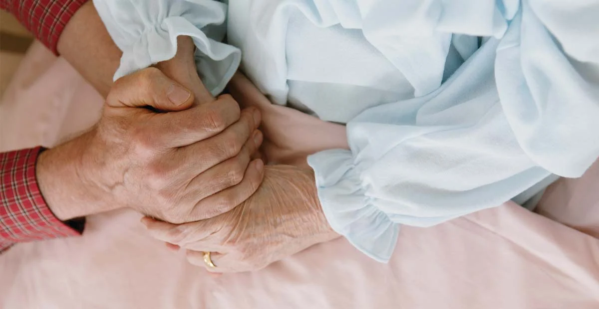 Closeup of person holding hands with a senior woman.