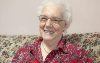 Smiling female resident seated on a couch.