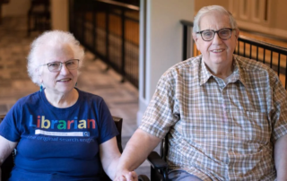 Portrait of the Francis's sitting together with a bowling alley behind them.