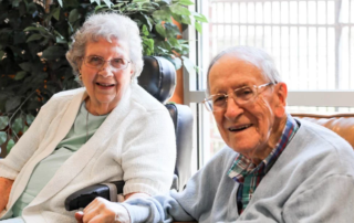 Portrait of the Whitacres, a senior couple, sitting together and smiling.