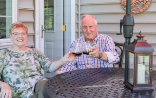 Residents Carol and Roy Smith raising glasses while sitting outdoors