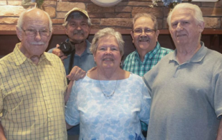 Group of smiling men and woman standing together indoors.