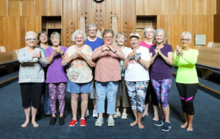 Group of smiling women posing together after Tai Chi class.