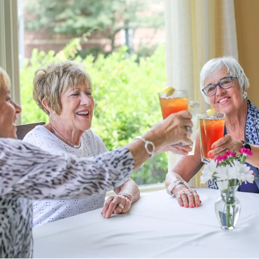 Untitled-13 group of women raising glasses at well-lit table with flowers