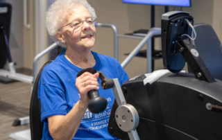 Senior woman working out on machine in fitness center