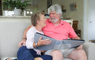 Smiling senior couple sitting together on couch with photo book