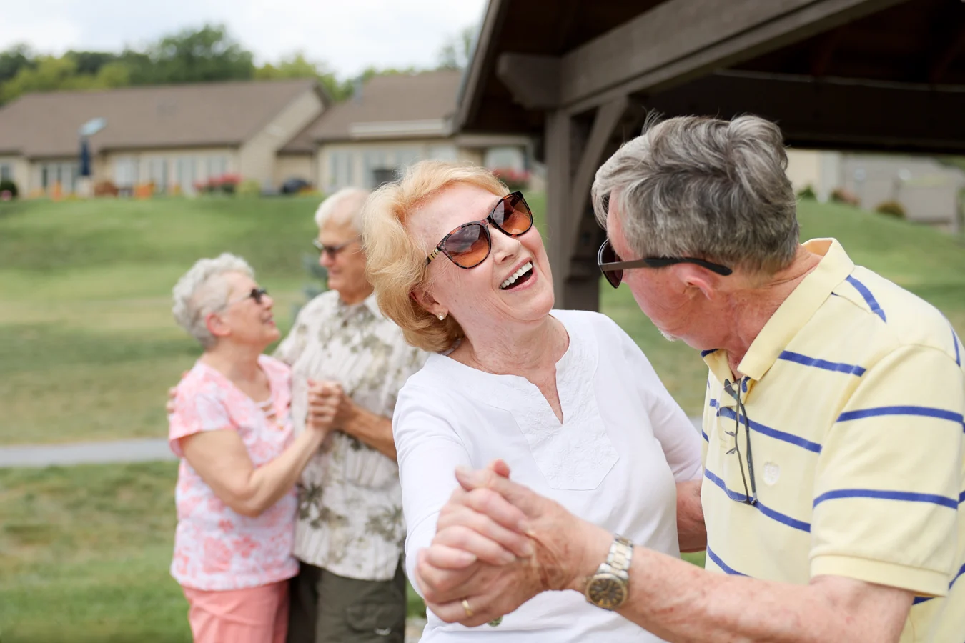 1W8A5812 Smiling couple dancing together outdoors with another couple dancing in the background