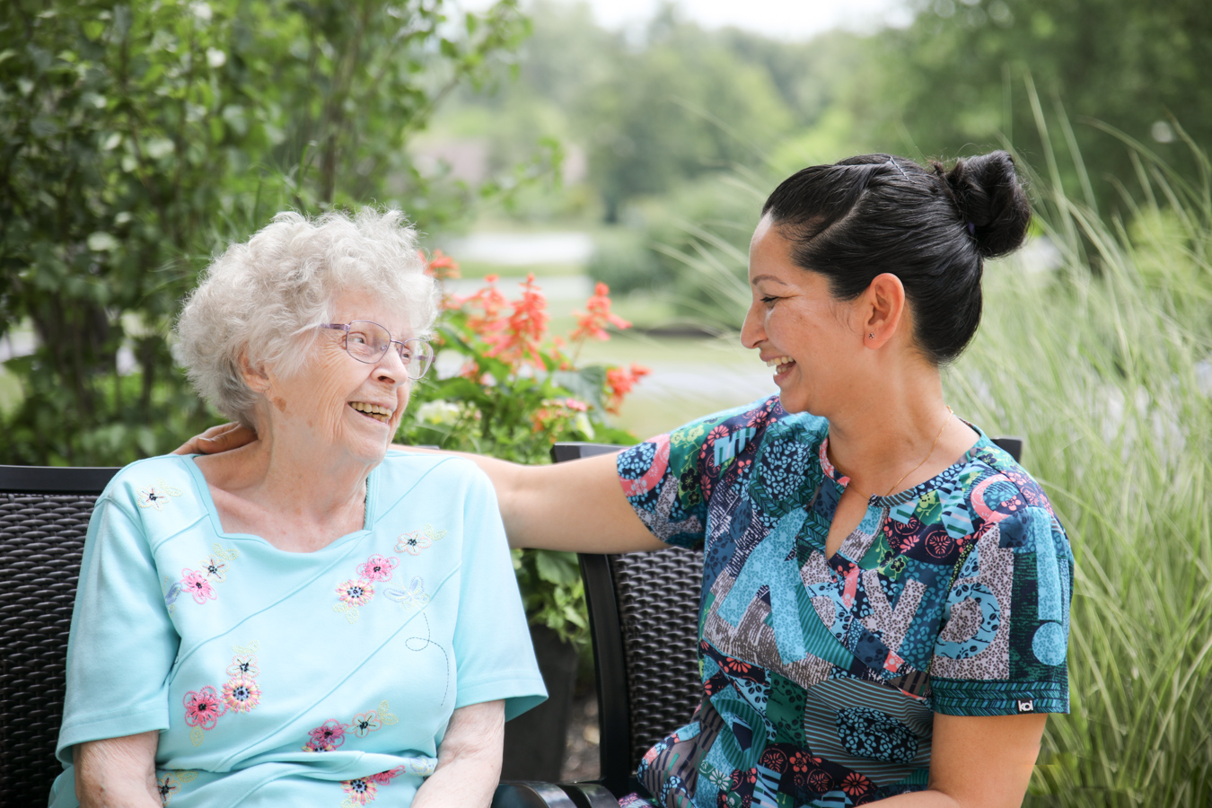Aide and resident smiling at each other outdoors
