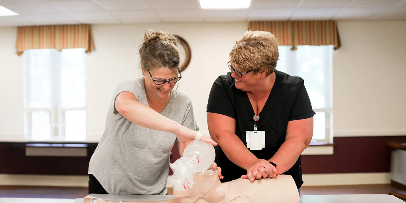 Two women training in CPR with dummy