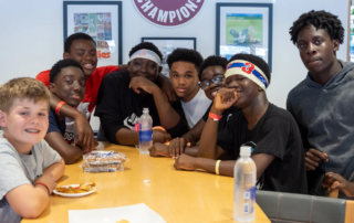 Group of Children's Home boys smiling at a stadium table during a Phillies game.