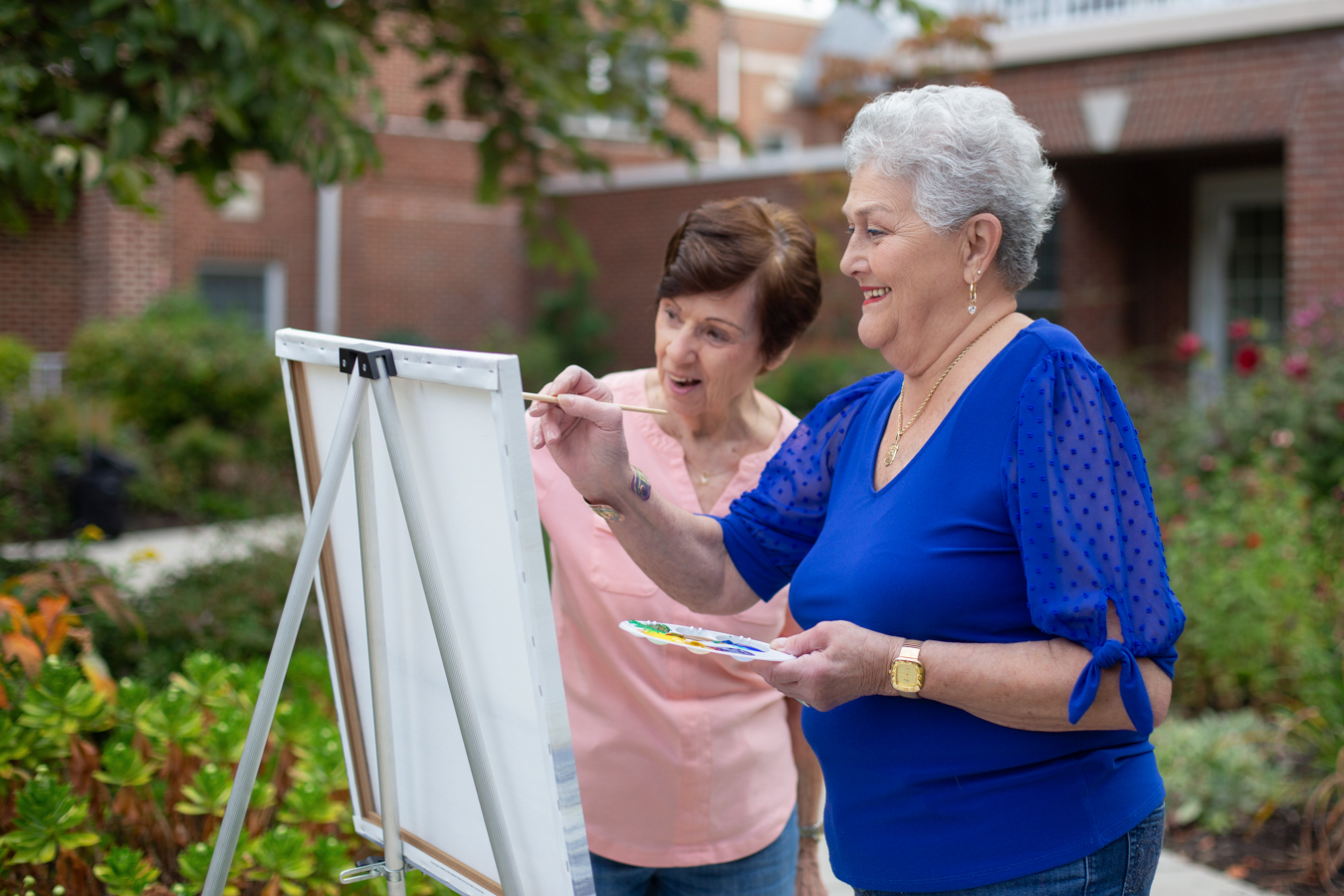 Two smiling women painting outdoor