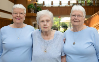 Three smiling women dressed in blue