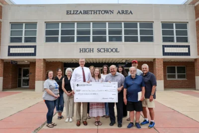 Smiling group of adults holding up a large check.