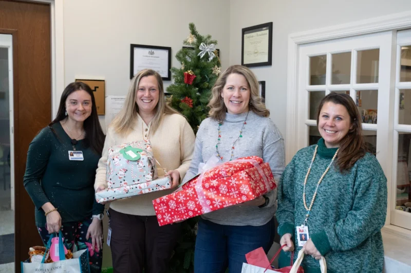 Smiling group of women holding Christmas presents.