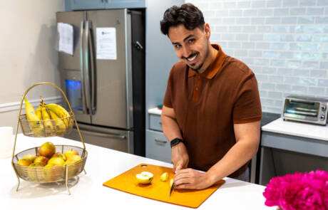 man smiling while slicing food on cutting board