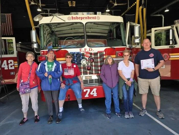 Smiling group of adults from the Bleiler Caring Cottage posed in front of firetruck.