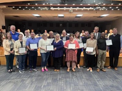 Smiling group of men and women holding up certificates.