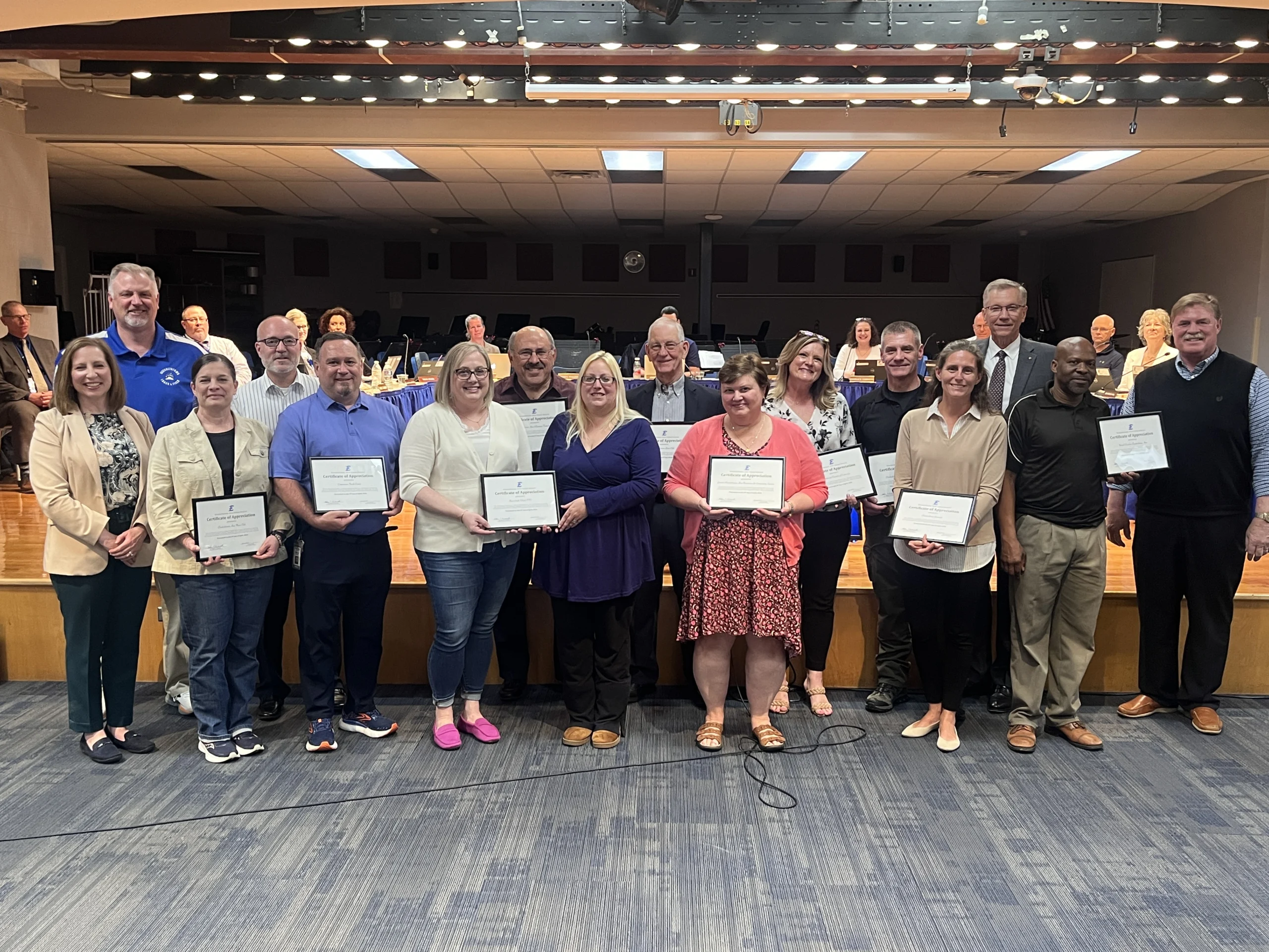 Smiling group of men and women holding up certificates.
