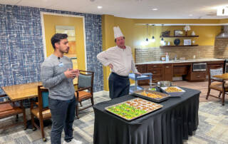 Dietician and chef standing at table with healthy snacks