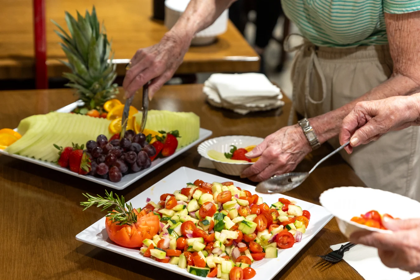 9I4A3240 Closeup of trays with fruit and vegetables with residents serving themselves.