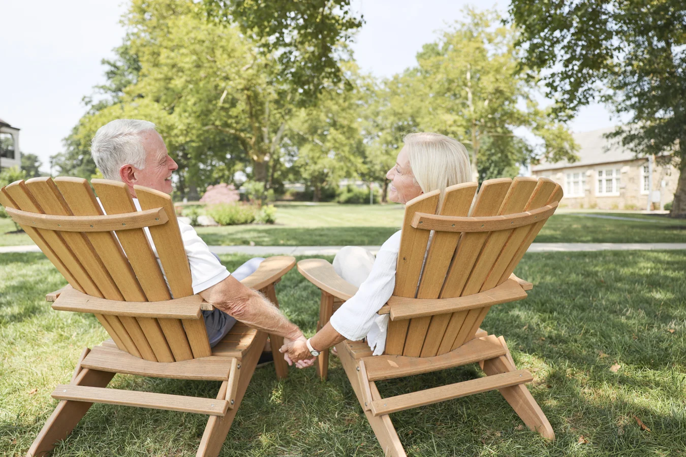 Couple sitting in chairs holding hands outdoors