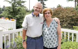Smiling couple standing together on their front porch.