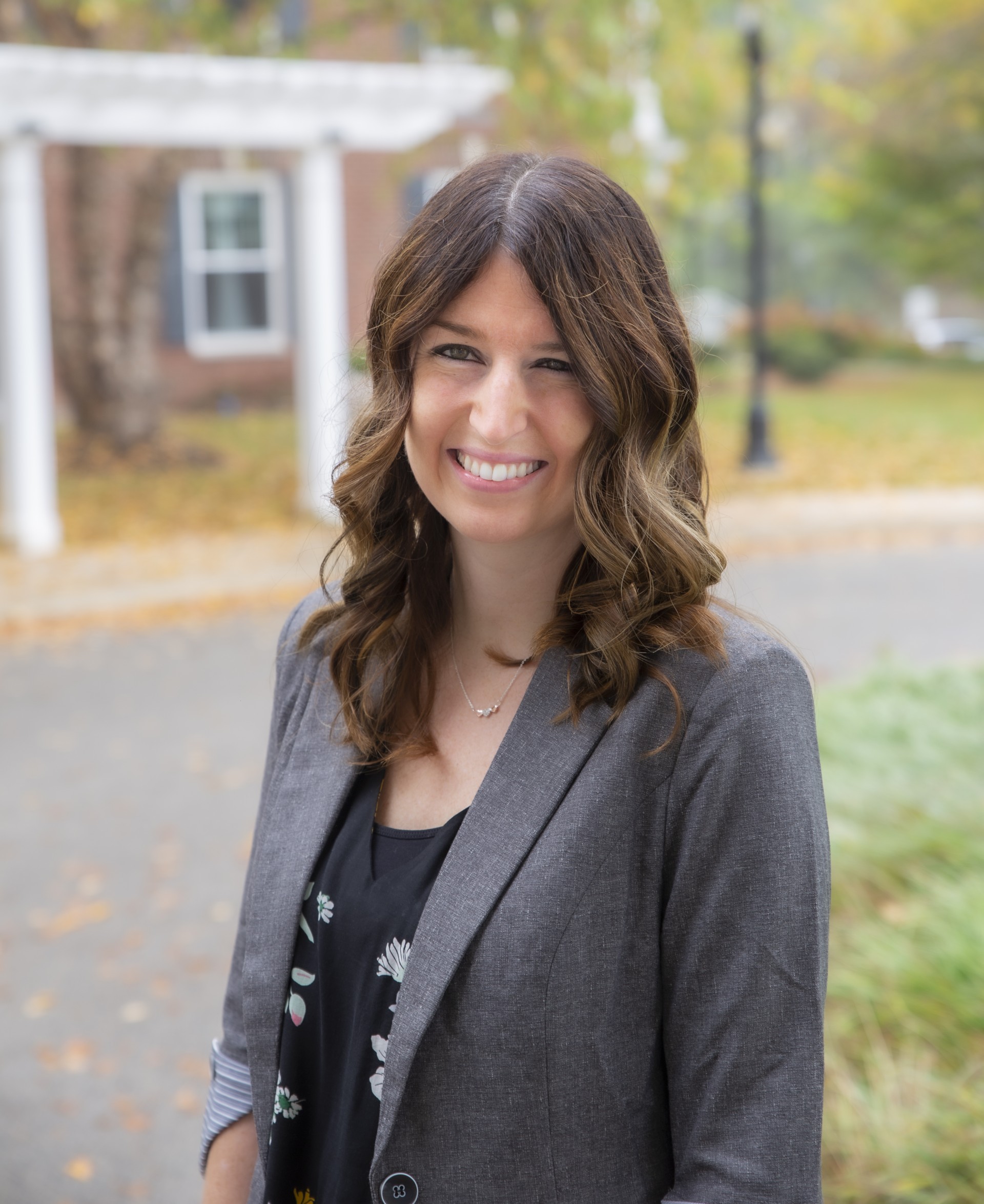 0d996eb5-c53e-4776-a0e6-01749eae476a Denise Jones, a smiling woman with long hair wearing a blazer and blouse while standing outdoors.