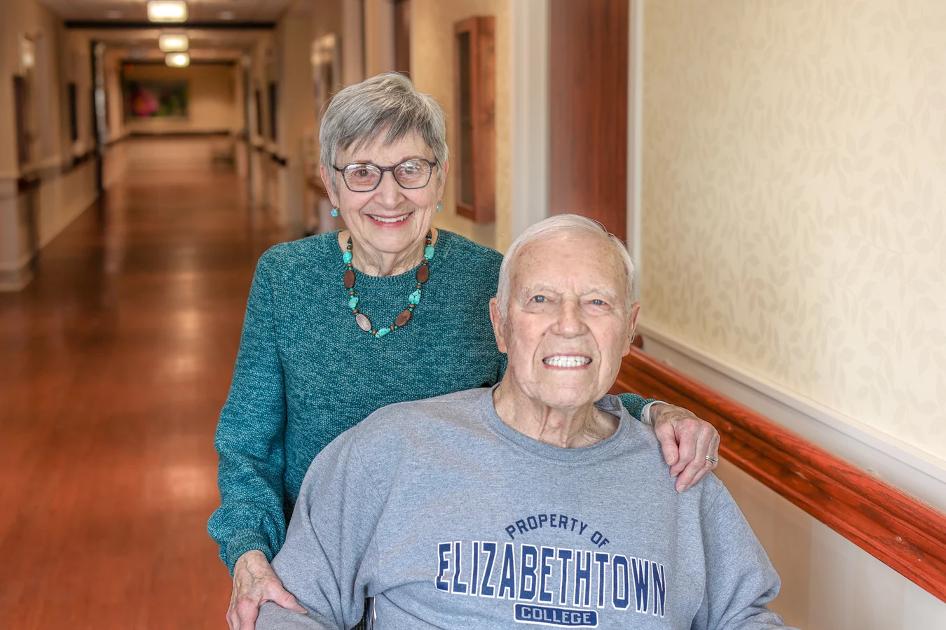 Smiling senior man and woman in hallway together.