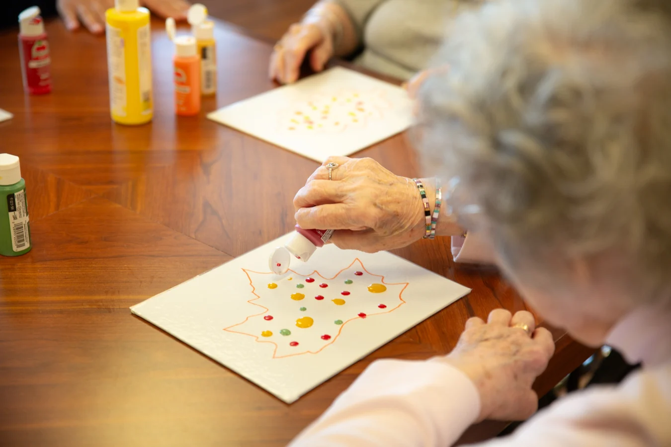 Closeup of a senior woman painting on the outline of a leaf.