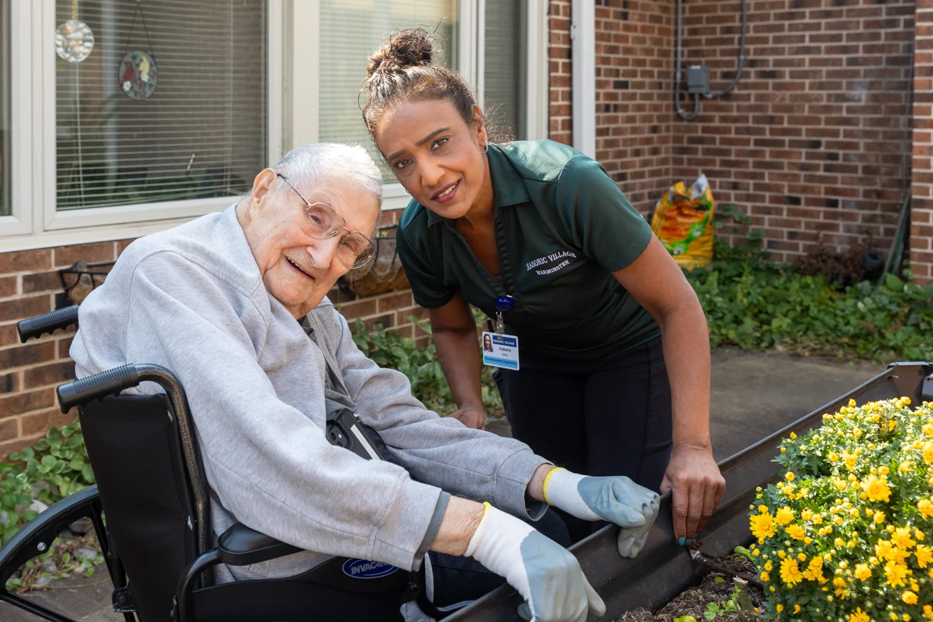 Nurse and smiling senior man working in a garden outdoors together.