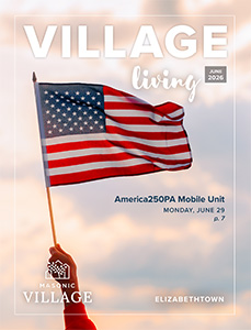 Elizabethtown Village Living magazine cover featuring a hand waving a flag with the sky in the background.