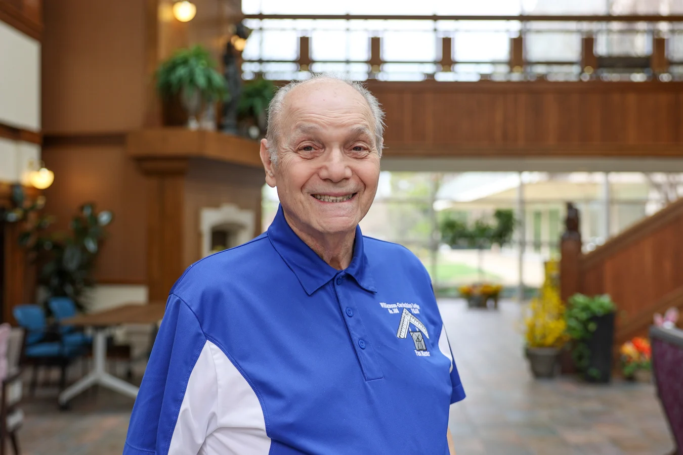 Smiling senior man standing in a well-lit lobby.