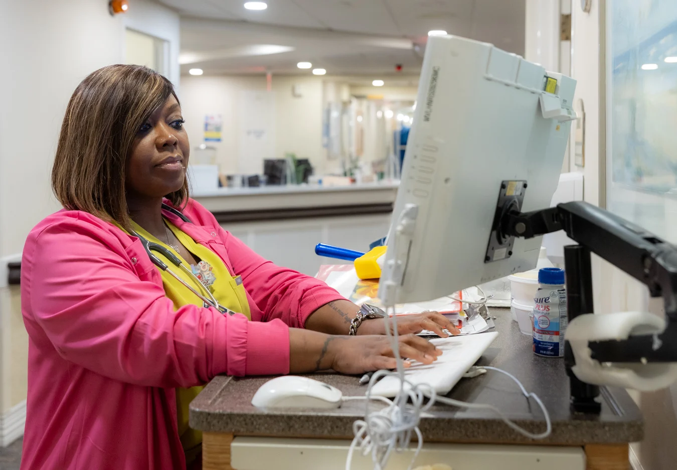 Nurse in bright-colored scrubs working at a computer station.