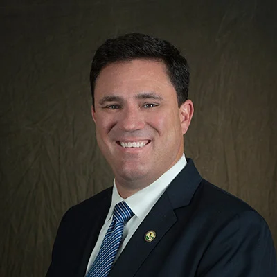 BillKingsbury3 William Kingsbury, a smiling man with short hair, dressed in a suit and tie standing indoors against a brown background.